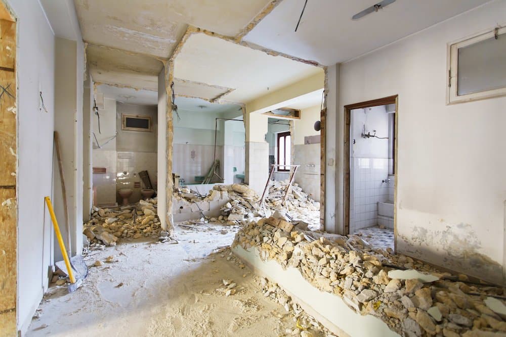 A view of the interior of a property where several walls have been taken down for renovation. The bricks and rubble sit 