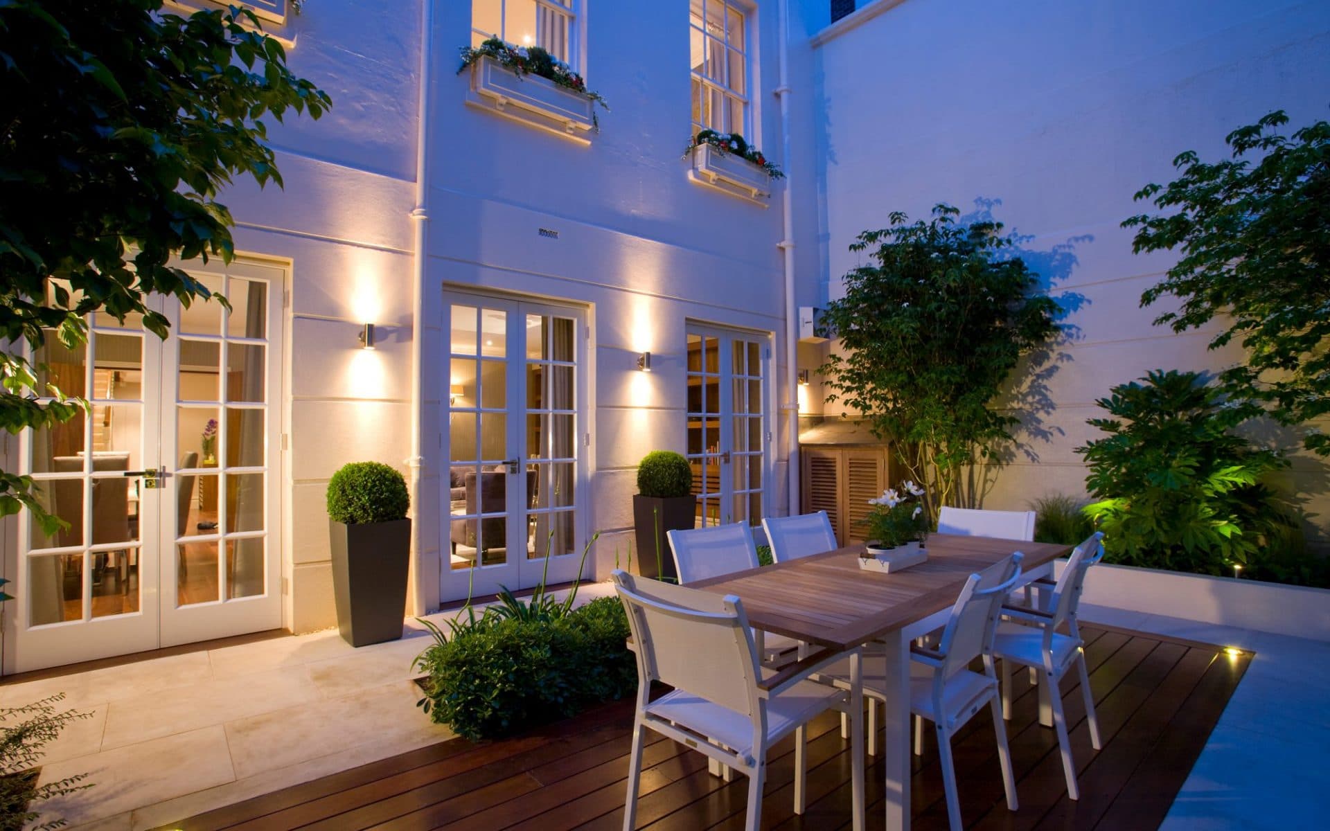 White exterior property with garden seating areas and trees as its surrounding